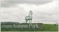 Metal frame statue of horse above large sign 'Glasgow Business Park'.