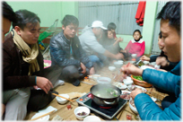 Diners on floor around steaming 'hot-pot'.