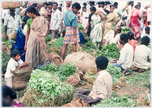 Crowds behind sellers with sacks of vegetables.