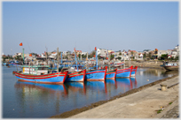 Line of moored red and blue fishing boats.