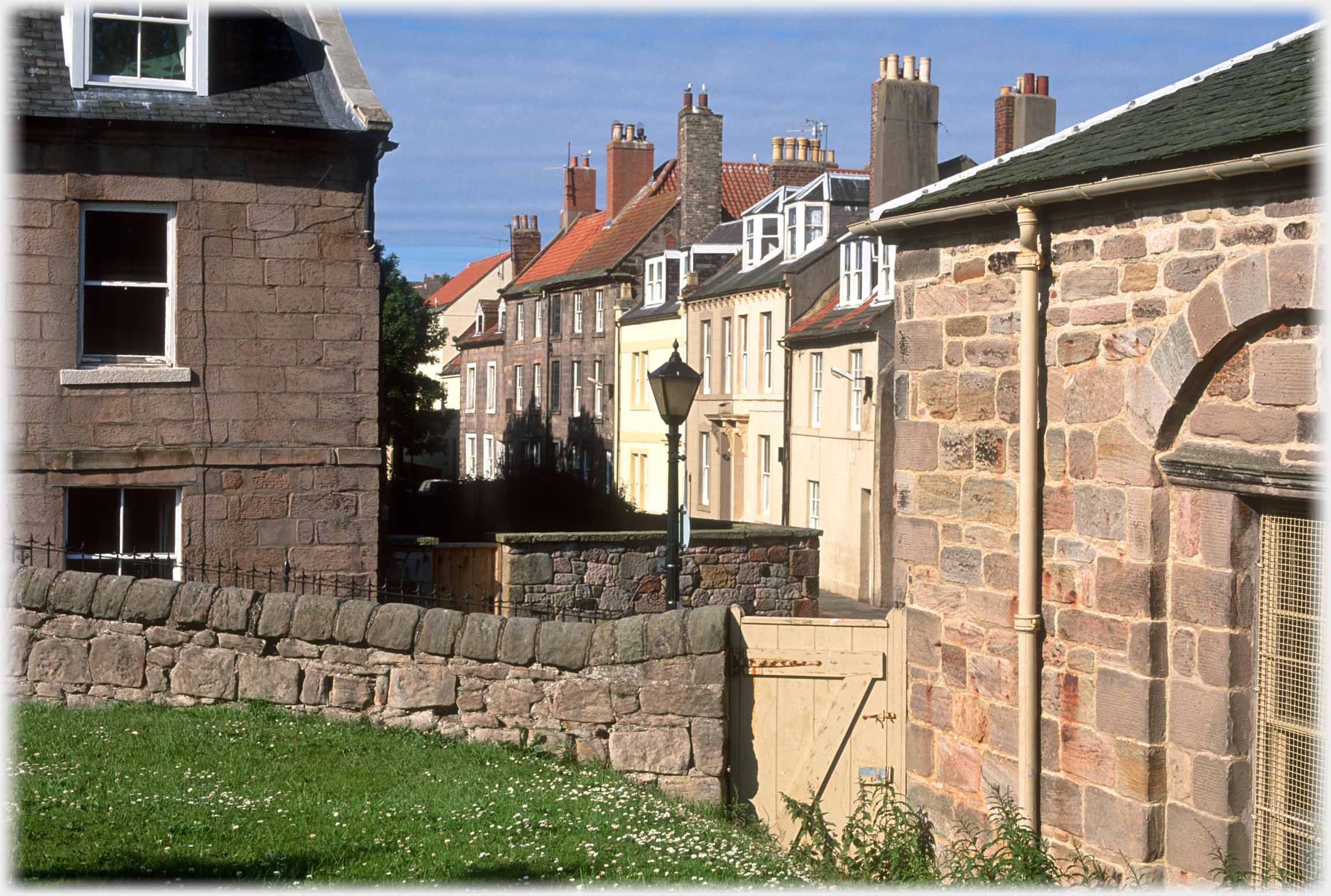 Looking between two buildings over two walls at row of houses.