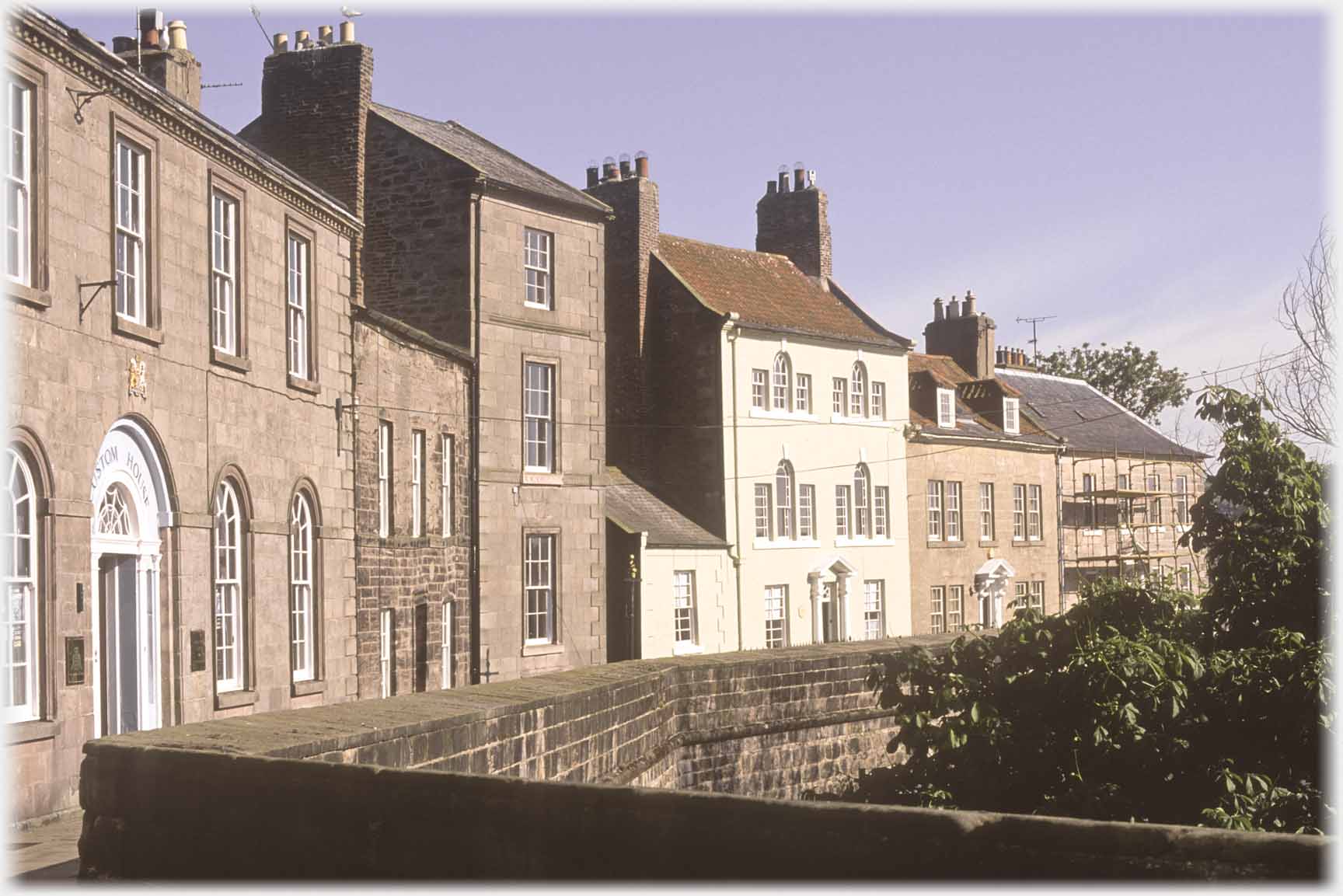 Row of Georgian windowed houses with wall in front.