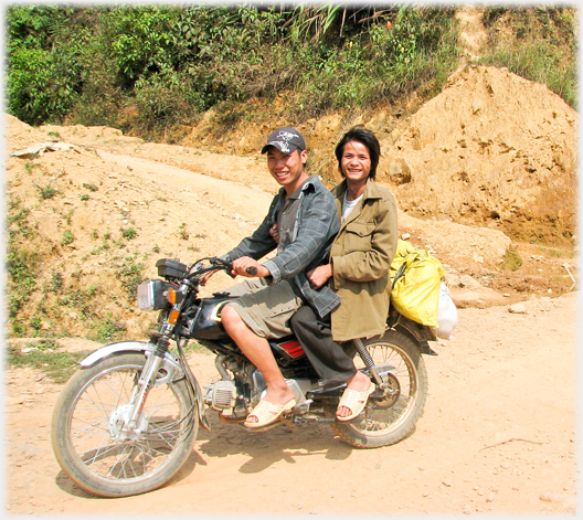 Two men smiling from a motorbike.
