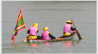 Three costumed people paddling a canoe.
