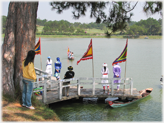 Costumed participants in boat race standing on jetty.