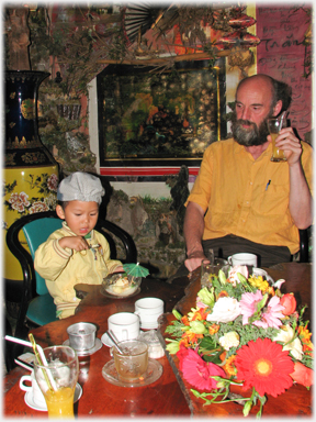 Man and boy inside cafe at table.