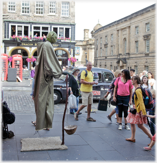 Man as Yoda statue being quizzically looked at by people.