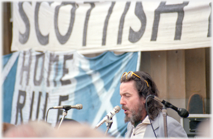 Speaker at microphone with banners behind.
