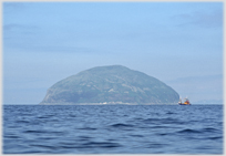 Dome shaped island with fishing boat near-by.