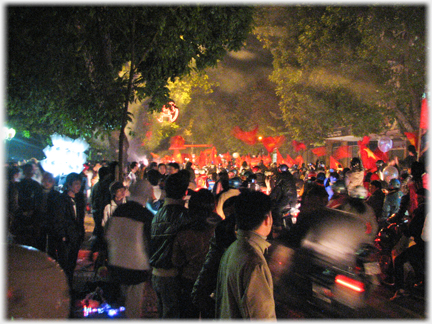 Night view of major street packed with people and flags.