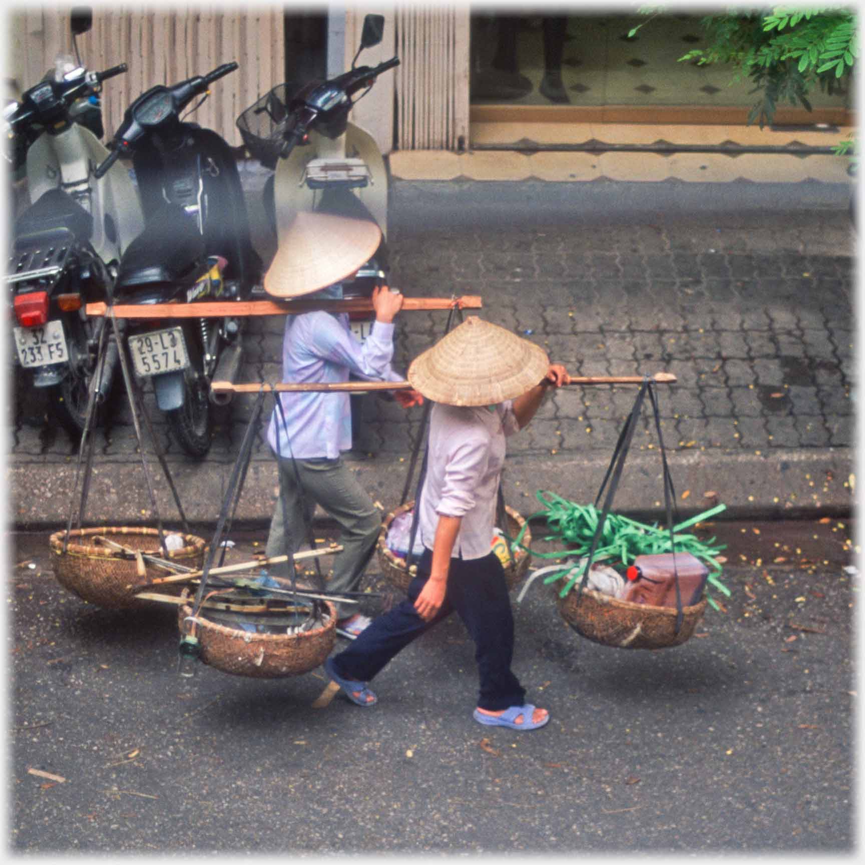 Two women walking together with mixed collection of waste in their pannier baskets.