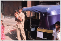 Man holding infant next to his Auto.