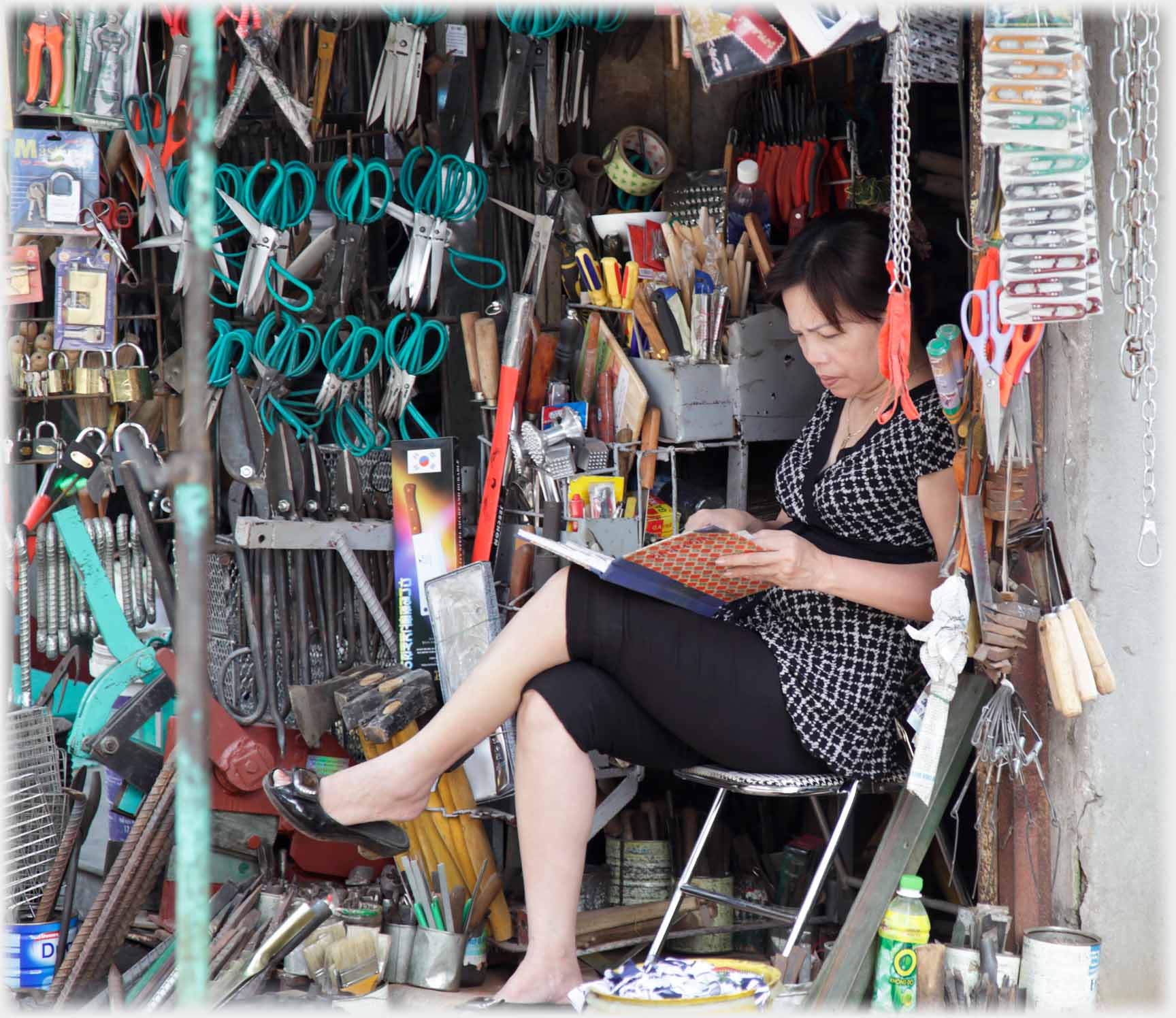 Woman sitting in small shop frowning at open note book.