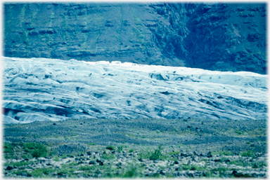 Glacier surface, grass foreground.