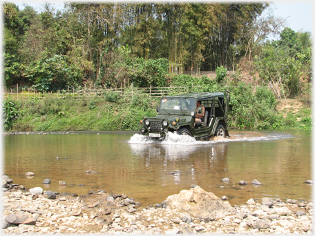 Jeep pushing through river water.