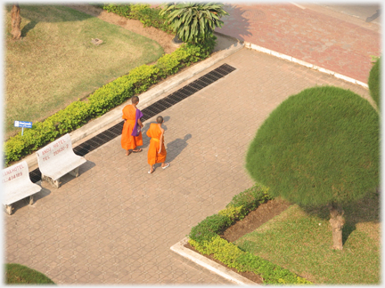 Two monks seen from above walking in a garden.