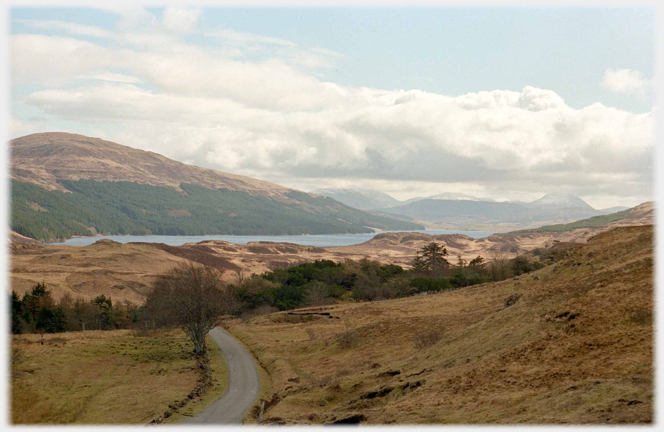 Small road running towards loch and hills.