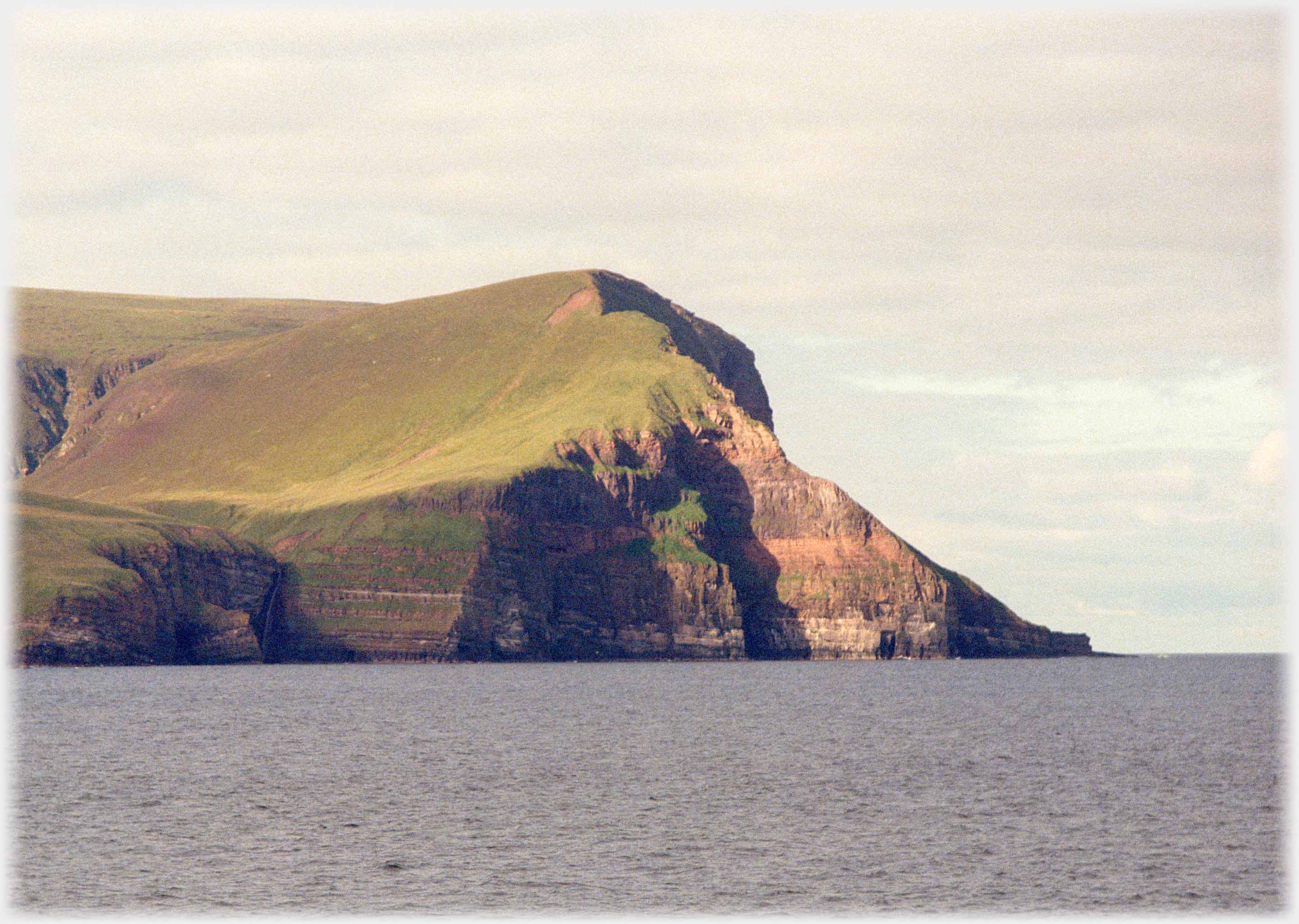 Cliffs with forty-five degree slope down to sea, sun  and shaddow on the cliffs surface.
