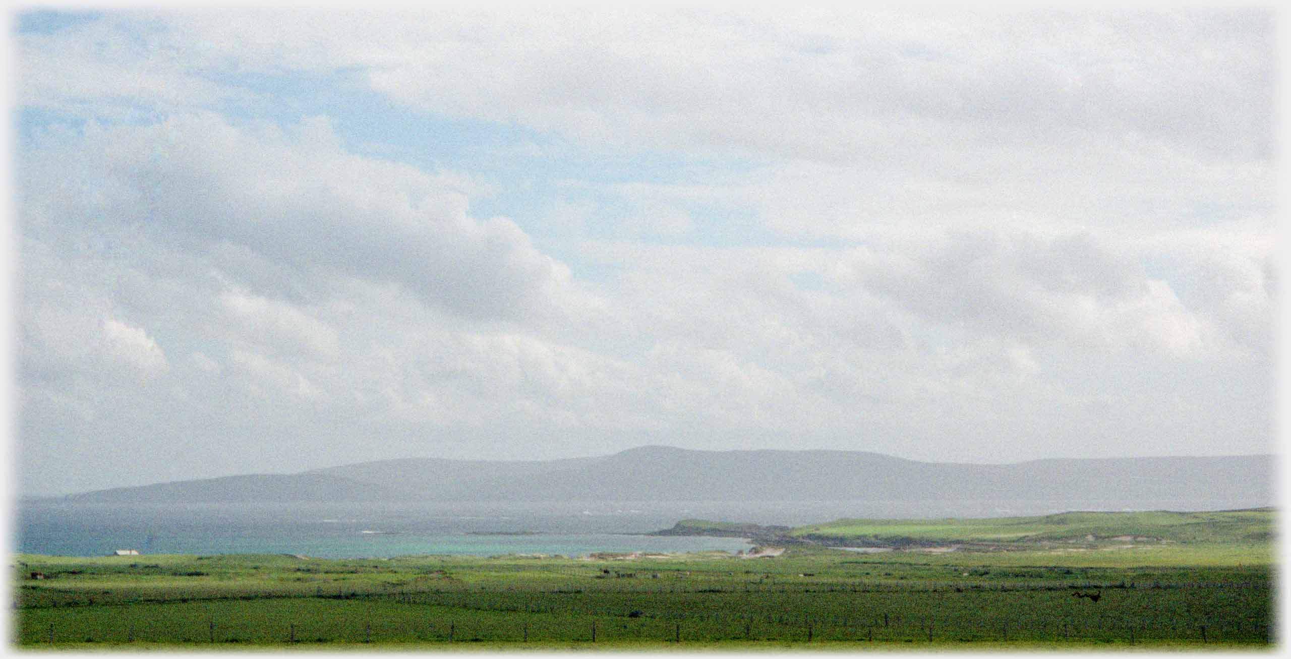 Looking over southern part of the island towards Westray under large sky.