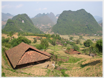 Large house roofs with karst hills as background.