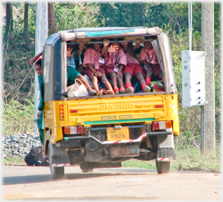 Children waving from the back of a departing auto.