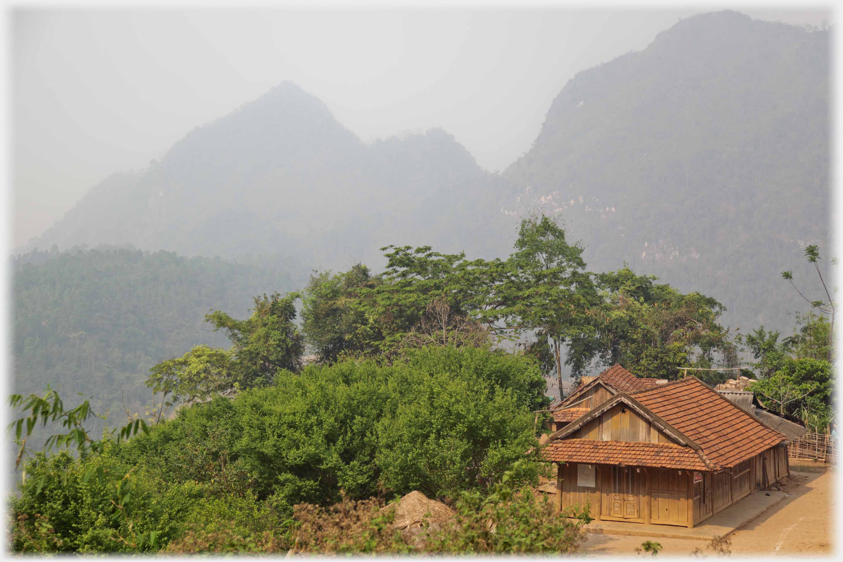 Large pan-tiled roof on house without pillared veranda, mountains in background.