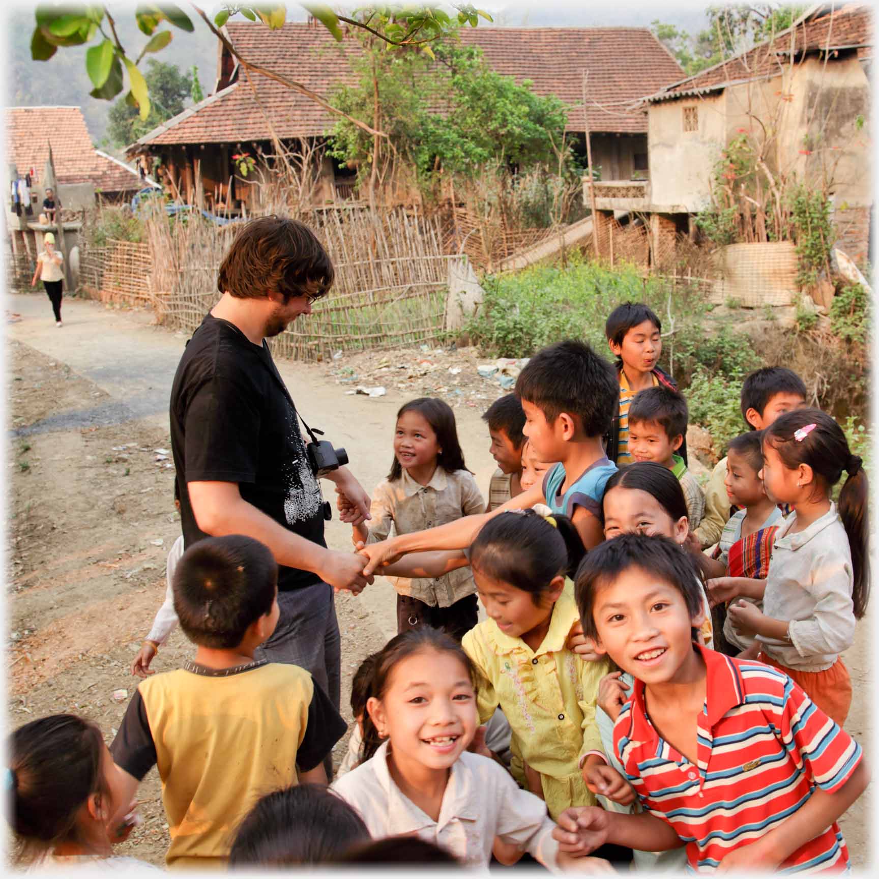 Western man shaking hands with a group of children.