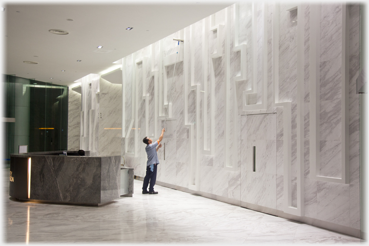 Man cleaning marble wall by reception.