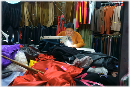 Seamstress surrounded by clothes.