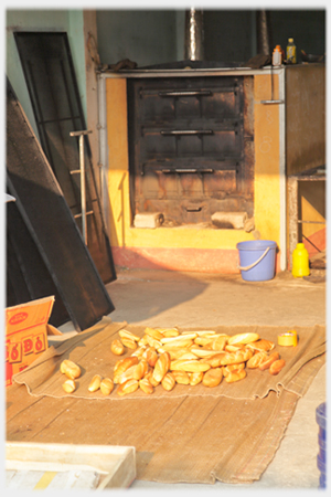 Bread oven with breads in heap on floor in front.