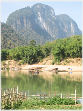 Tower karst in background, river shore and boats in foreground.
