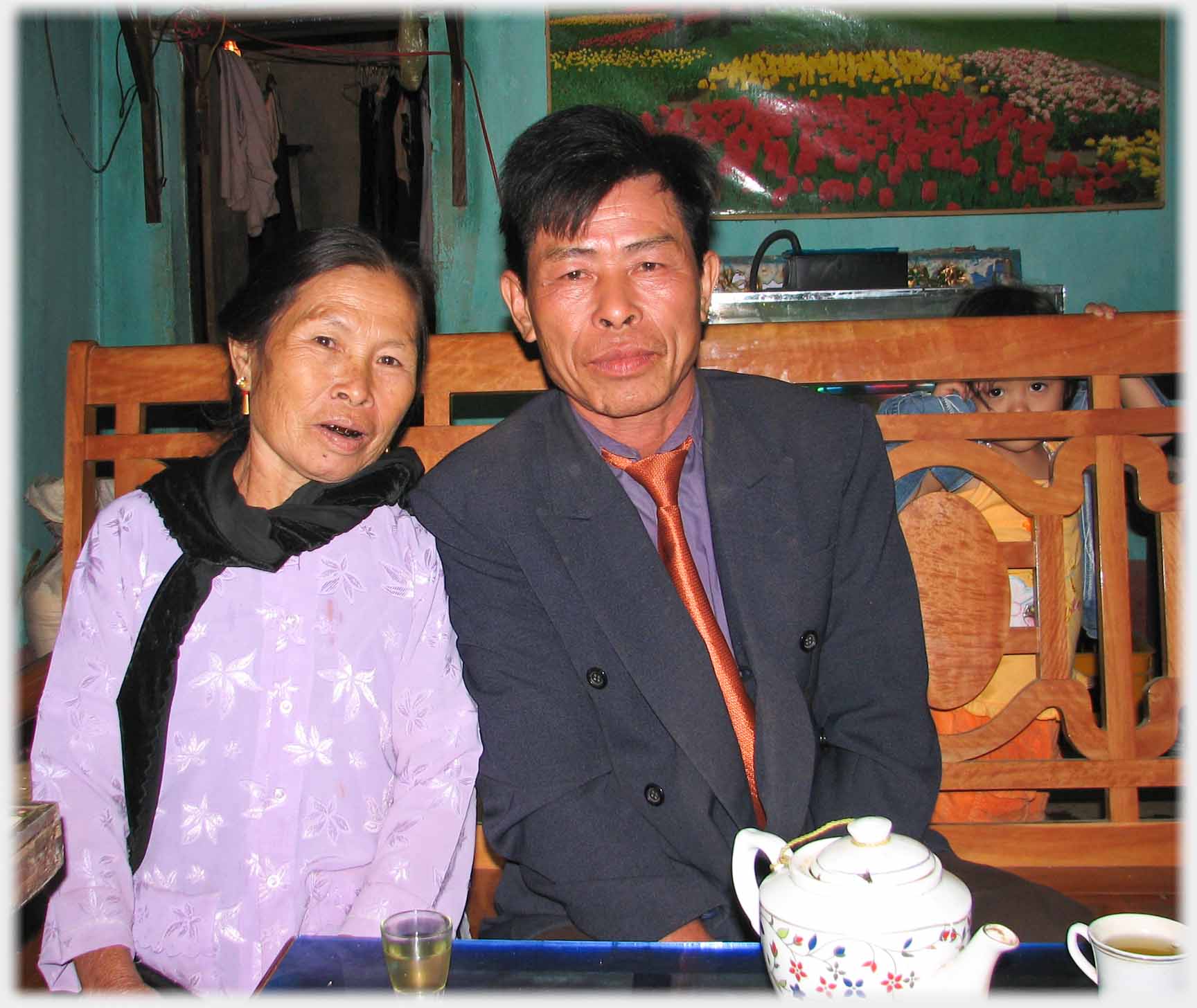 Man and woman sitting by teapot, tea glass and tea cup.
