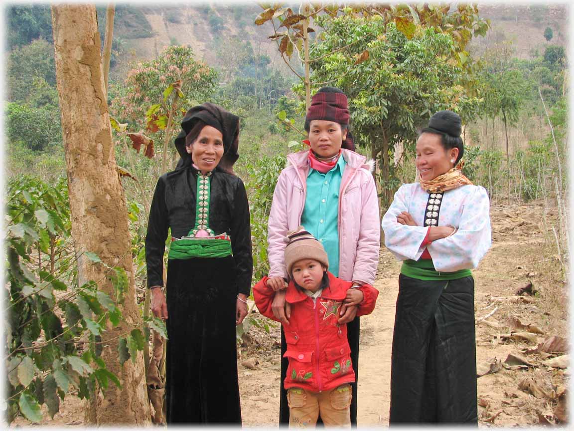 Three women and child by coffee plant.