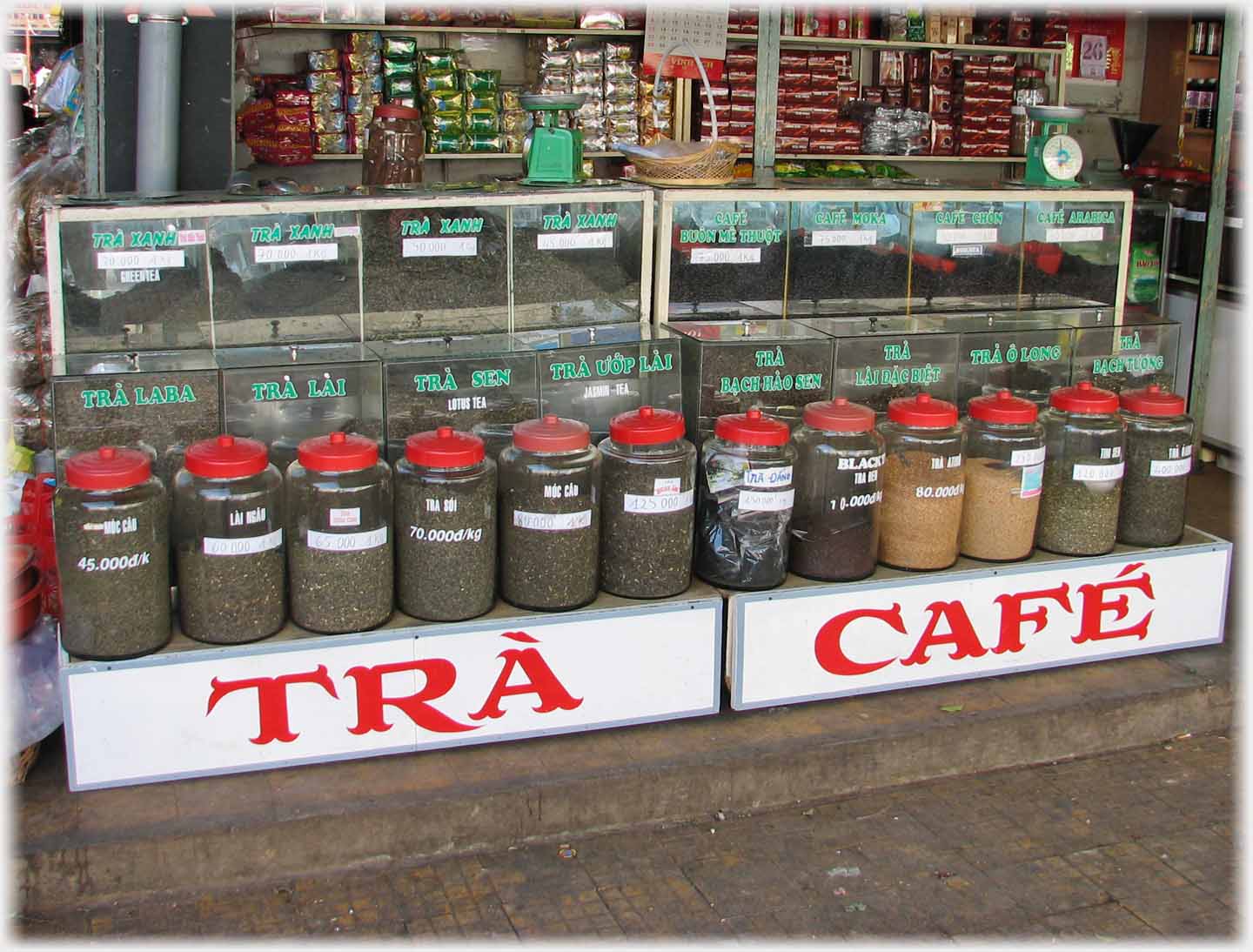Front of stall with two large words and a dozen glass jars in front of cabinets of tea.