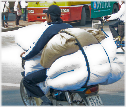 Man with large soft bags infront and behind him.