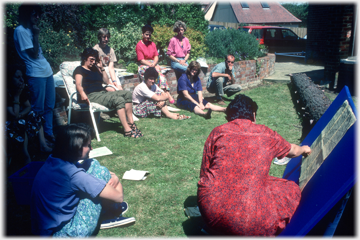 Group sitting around on grass watching teacher.