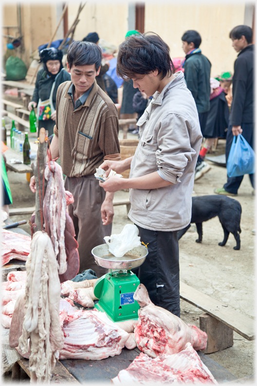 Two men beside meat stall.