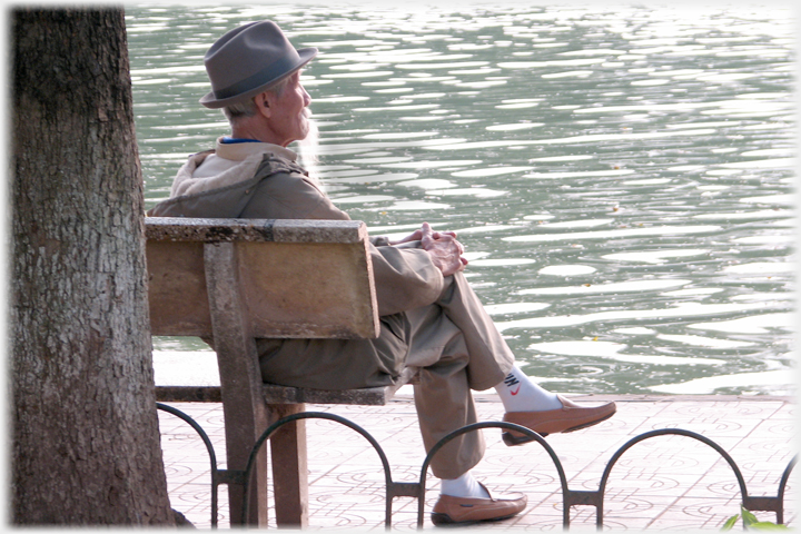 Bearded man siting by rippling water.