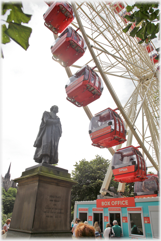 Statue next to the gondolas of a Ferris Wheel.