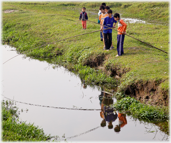 Boys by stream with fishing rods.