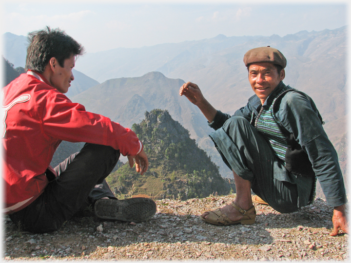 Man cutting tree trunk, and two cranes lowering beam into place.