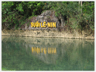 Large words on rocks reflected in river.