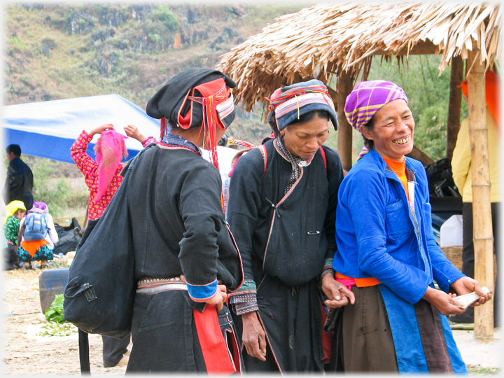 Three women passing money between them in a market.