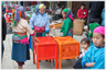 Women standing beside a small cupboard/table.