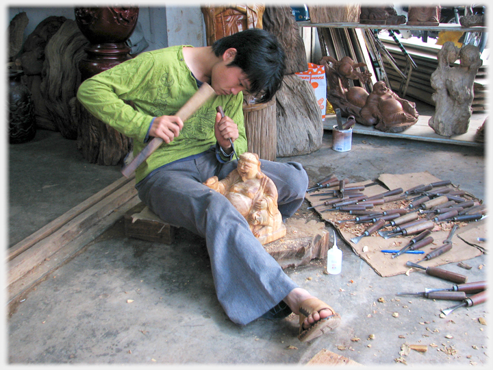 Figure carver hammering a chisel.