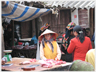 Woman with large glasses behind meat stall in market.