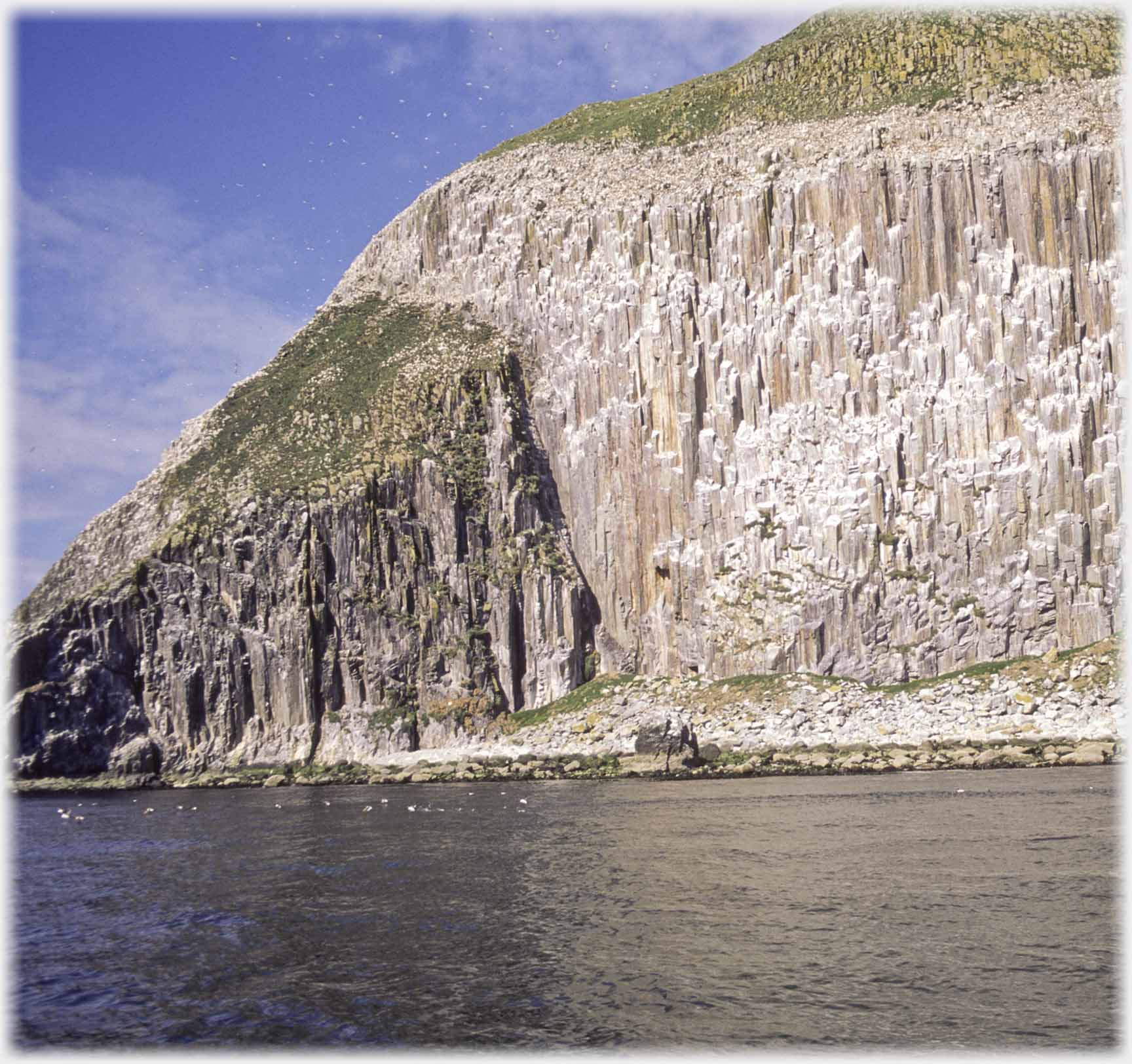 Cliffs, distant birds swimming.