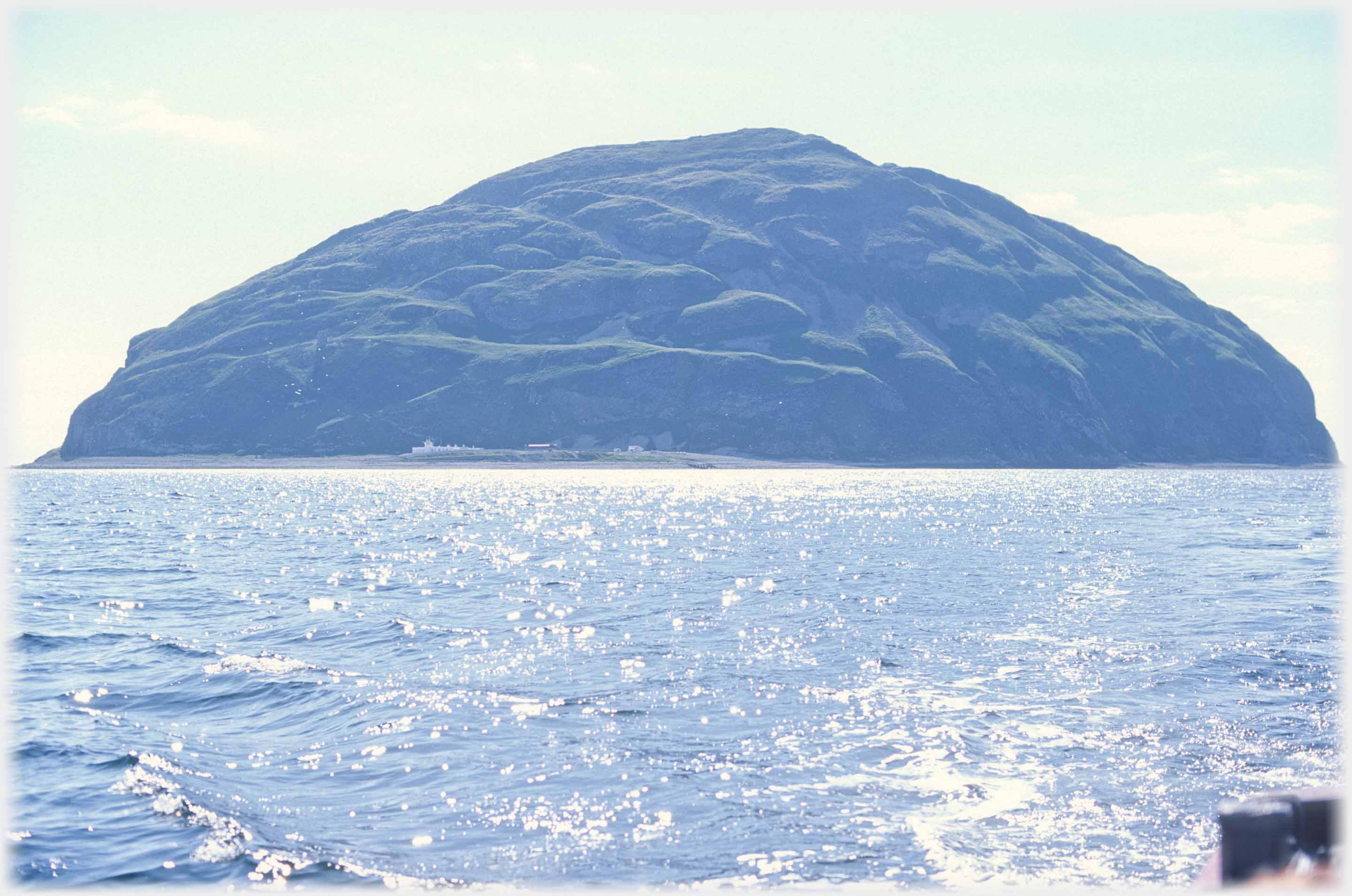 Island seen with strong side light and wake of boat.