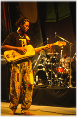 Man on stage playing curious shaped guitar.