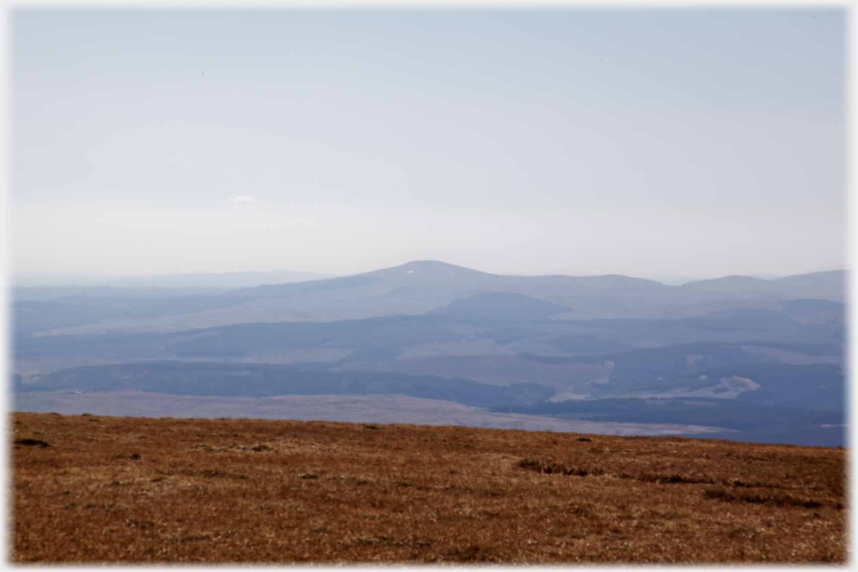 Distant volcano shaped hill rising out of gloom.